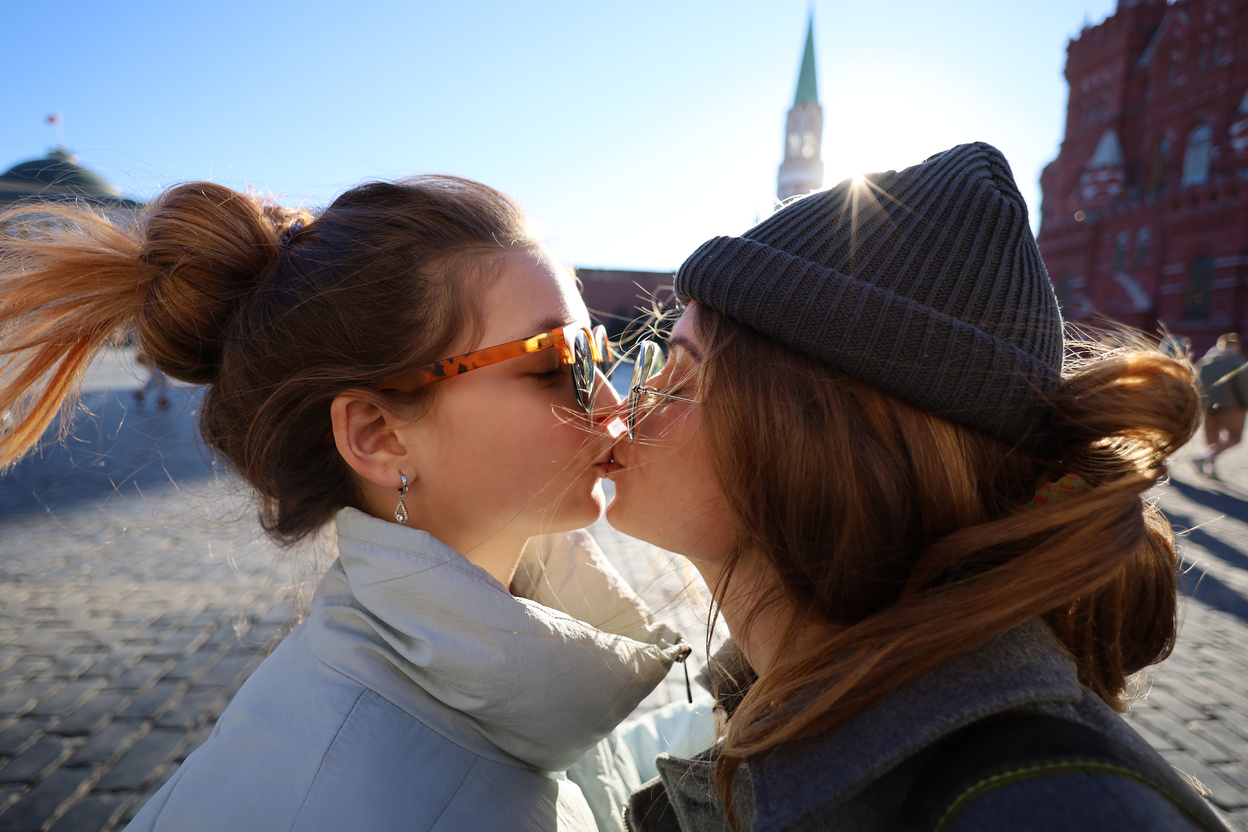 A Same Sex Couple Kissing Each Other while Wearing Sunglasses